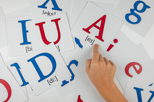 English language learning: child pointing at a card with letter A and phonetic transcription