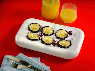 Griasoli Pasta is beautifully arranged on a white platter, showcasing its unique shape and colors. Alongside, a glass of orange juice adds a cheerful touch to the bright red table setting