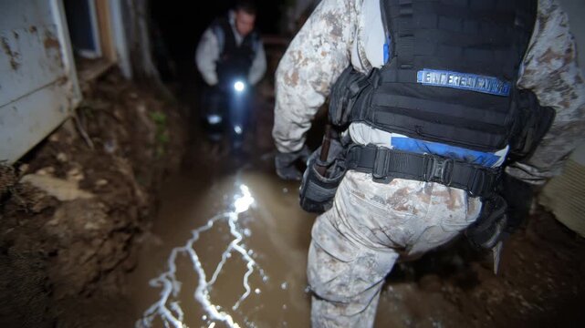 446Wide-angle view of inspector walking through dark basement, flashlight beam illuminating cracked walls and puddles, tools in utility belt, emphasizing home foundation maintenance