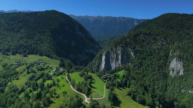 Carpathian Mountains, dramatic limestone cliffs of Zarnesti Gorges near Pestera village with view to jagged Piatra Craiului ridge on a clear summer day