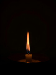 Close-up of a single burning candle, its flame illuminating the deep darkness, symbolizing warmth, hope, and peace.