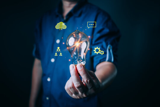 person hold a glowing light bulb symbolizing creativity, innovation, digital transformation, and new ideas with cloud, communication, and technology icons floating around for modern business concepts. - Powered by Adobe