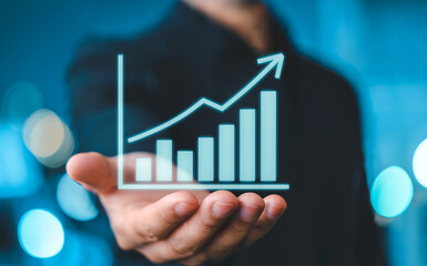 A persons hand holding a glowing digital graph showing upward trend and growth, symbolizing business success, financial progress, and positive economic development