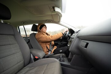 A young driver sets off on an adventurous journey, navigating through misty and fog-laden landscapes in their compact car during the early hours of the morning