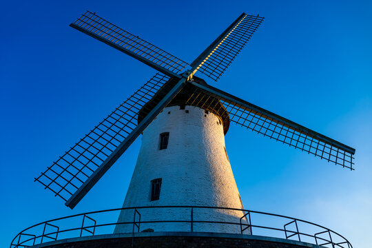 Historic windmill from 1823 in Krefeld-Traar on the Lower Rhine (Germany) on a sunny morning with blue skies. Iconic architectural monument and Dutch-style landmark from frontal frog perspective.