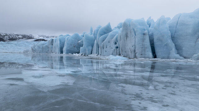 Aerial view of icy sculptures rise majestically from the frozen lagoon, their pale blue hues mirrored in the still, icy waters, Jokulsarlon, Sveitarfelagid Hornafjordur, Iceland.