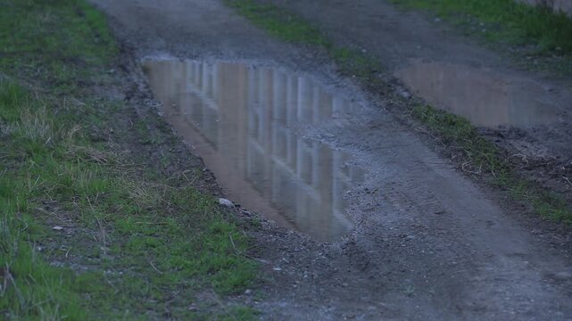View from a moving vehicle showing a lake with a water tower in rainy weather and a winding mountain road with a sharp turn warning sign.


