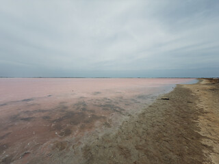 Spectacular landscape of a pink and salty lagoon under a cloudy sky