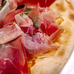 White pizza with prosciutto crudo, arugula and parmesan