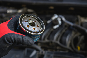 Auto mechanic holding an old oil filter that has been used