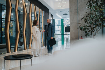 Two professionals greet with a handshake in a sleek, glass-walled lobby. The scene conveys...