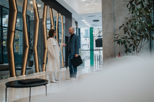 Two professionals greet with a handshake in a sleek, glass-walled lobby. The scene conveys collaboration, professionalism, and mutual trust in a contemporary corporate environment.