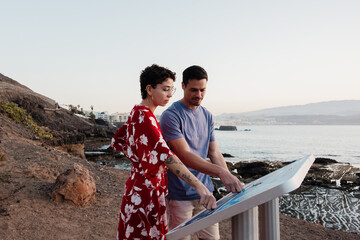 Couple reading tourist information map on Canary Islands coastline