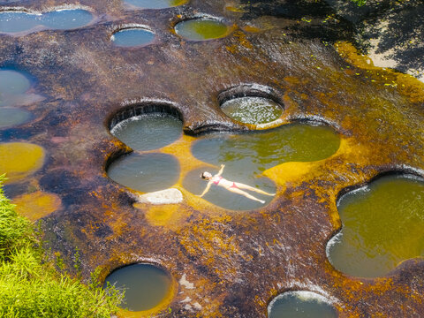 Aerial view of a woman floats serenely in one of the many natural pools of Las Gachas, the river of seven colors, Guadalupe, Santander, Colombia.
