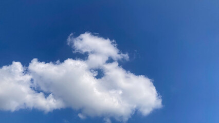Vibrant blue sky with fluffy white cumulus clouds on a bright sunny day, perfect for use as a serene and clear background.