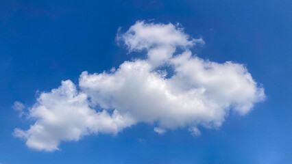 Fototapeta premium Vibrant blue sky with fluffy white cumulus clouds on a bright sunny day, perfect for use as a serene and clear background.