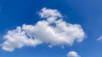 Obraz premium Vibrant blue sky with fluffy white cumulus clouds on a bright sunny day, perfect for use as a serene and clear background.