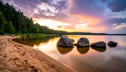 Picturesque lakeside sunset with golden sky, trees, and rocks