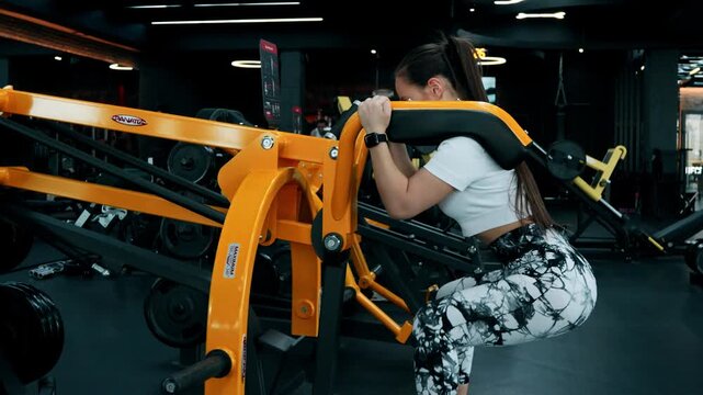 The woman is performing a pull-up exercise on a gym machine