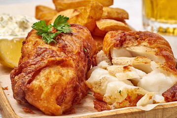Tender fish and chips beneath crispy golden coating, fried fish with aromatic batter and flaky texture showcased