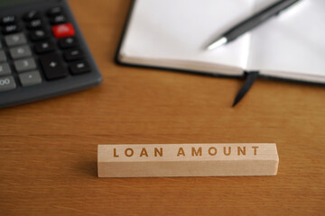 Loan amount. Financial concepts. Words written on a wooden block with office supplies in the background.
