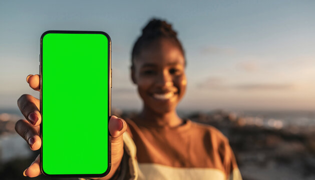 shot of Cheerful young woman presenting a smartphone with a green screen, ideal for copy-space. Selective focus on phone for technology and app design mockups
