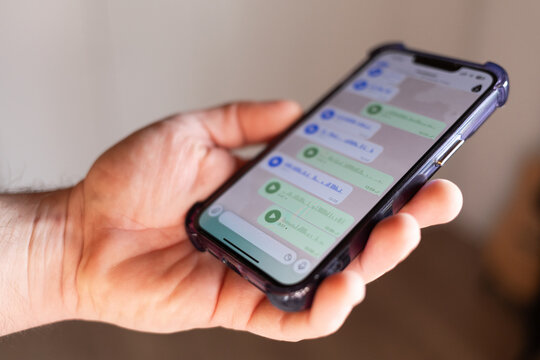 Melle, Germany - October 23, 2025: Man holding smartphone displaying WhatsApp app with colorful chat messages and copy space for design