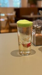 Refreshing cocktail with foam and flower garnish on table in cafe setting