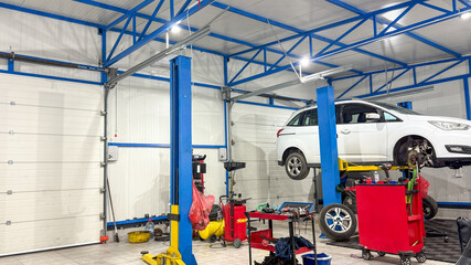 White car suspended elegantly in a brightly colored auto garage, reminiscent of Frankenstein Day and National Mechanics Appreciation Month
