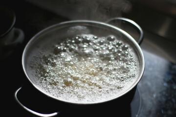 Cooking pot with boiling water and steam. Cooking at home. Selective focus.