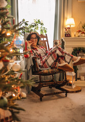A woman in a checkered pyjama is drinking tea in a Christmas interior