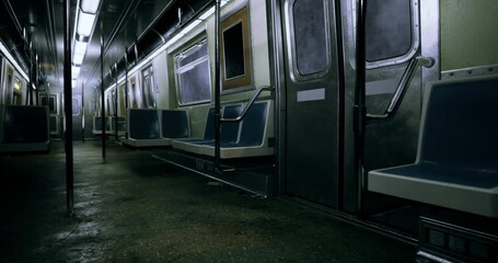 A deserted subway train interior showcases empty blue seats and dim lighting. The metal surfaces reflect slight illumination, creating a quiet atmosphere late at night.