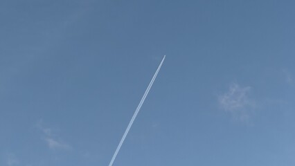 Ethereal contrail slices azure sky, whispering of wanderlust and Imbolc celebrations, celestial canvas, atmospheric poetry, opaque horizons