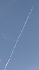 A lone contrail scratches the azure sky, evoking Solstice journeys and celestial navigation's ethereal whisper