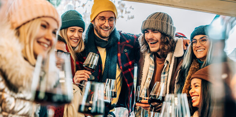 Happy multiracial friends toasting red wine at restaurant terrace - Group of young people wearing...