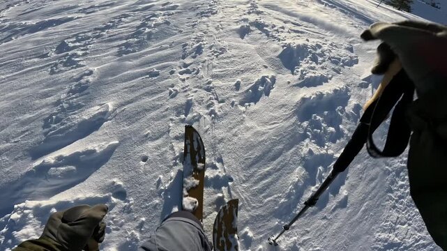 First person view of splitboard touring uphill on powder snow, deep snow ascent in bright winter sun