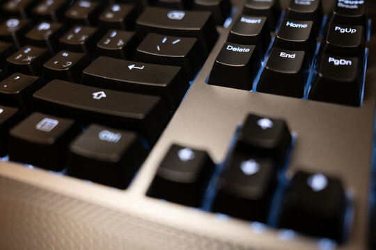 Close-up of a modern black keyboard with blue backlighting. Macro shot with a shallow depth of field, perfect for technology or gaming concepts. - Powered by Adobe