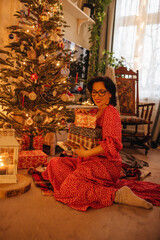 a woman with gifts under the Christmas tree