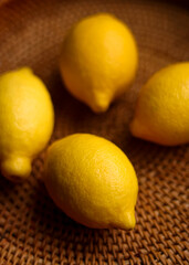 Four whole lemons arranged on a brown wicker background, symbolizing healthy living, natural food, and vitamin C