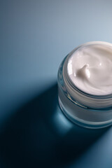 Creamy white moisturizer in an open glass jar. Concept of beauty, skincare, hygiene, and daily...