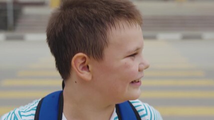 Schoolboy stands on crosswalk near car for safe passage, Student waits at zebra crossing making sure the way is clear, Kid cautiously stands at pedestrian crossing with blue backpack on, Boy observes - Powered by Adobe