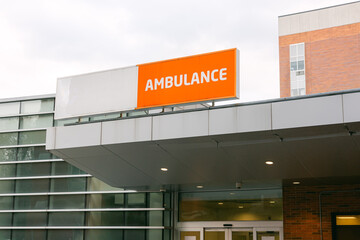 Obraz premium Bright orange ambulance sign visible at hospital entrance on a cloudy day