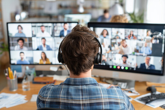 A man wearing headphones is sitting in front of two computer monitors