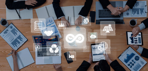 A dynamic business meeting showcases professionals collaborating over sustainability and technology trends while engaging with digital devices, fostering innovation. Trope