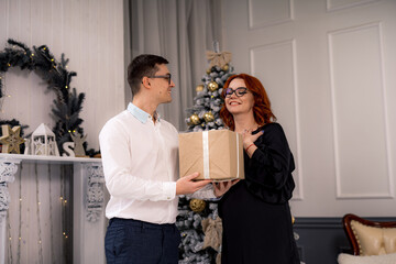 Couple exchanging a present. Couple stands together exchanging present in festive room.