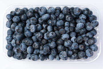 Blueberries in a plastic container isolated on a white background.