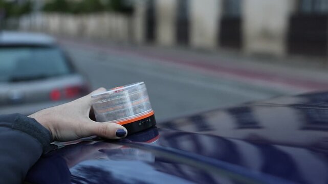 Driver placing an amber v16 emergency flashing light on the car roof during a breakdown