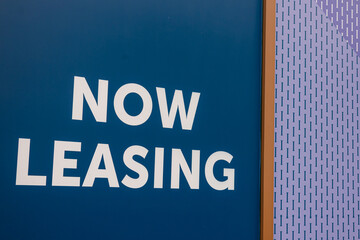 Sign indicating availability for leasing in a modern building at a busy urban location