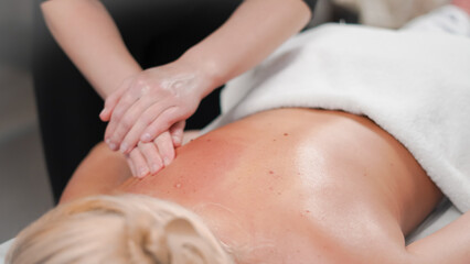 Gentle massage hands working on blonde client creating calm salon atmosphere.
