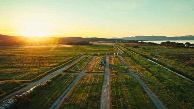 Stunning aerial drone footage of a van parked in open fields beside the sea at sunrise, freedom and travel essence